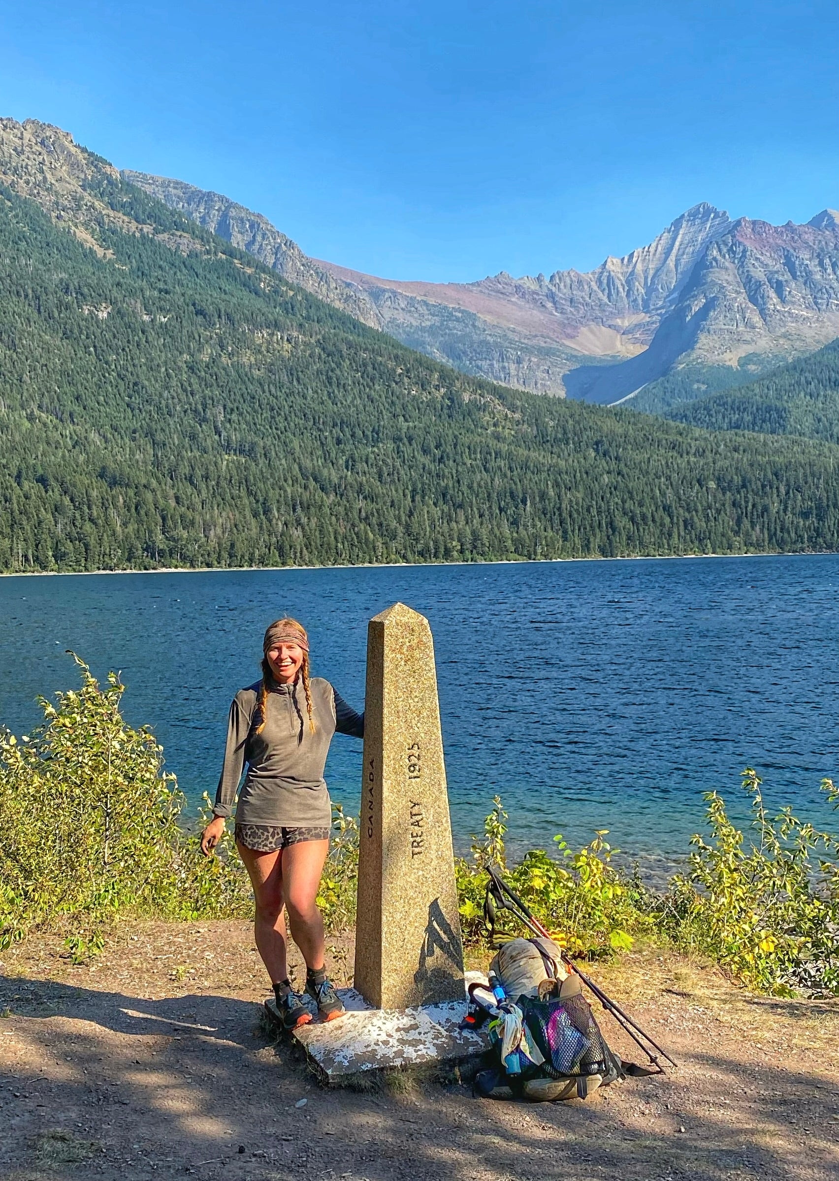 Thru-hiker Carol "Cheer" Coyne standing at the CDT finish and northern terminus at Waterton Lake on the Canadian border.